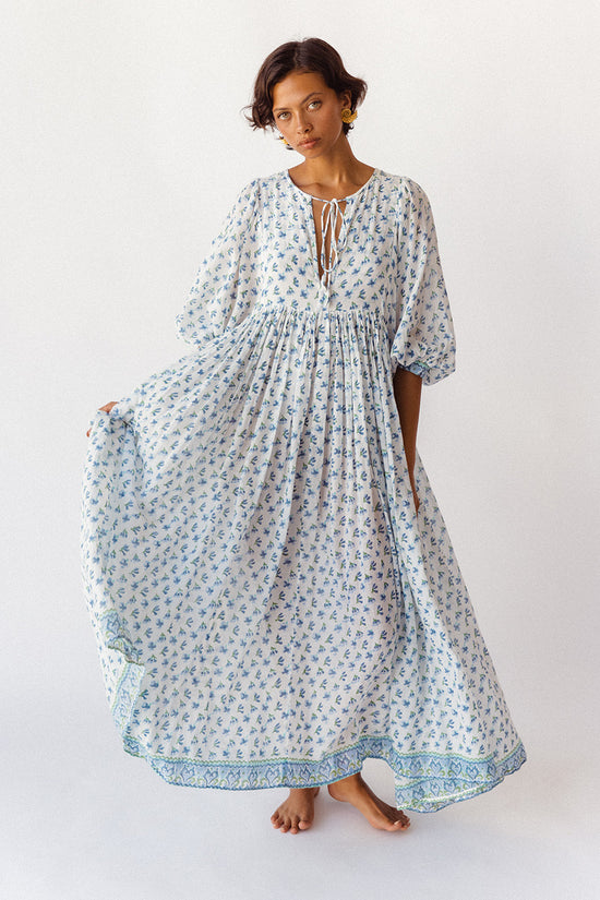 Daughters of India Kyra Maxi Dress in Azure — studio front holding skirt, neckline tie and border hem detail